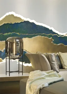 A modern living room features a lamp on a metal stand next to a gold-framed sofa with pillows and a gold blanket.