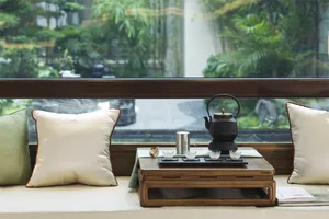 A modern living room featuring wooden furniture, green cushions, and a small table with a teapot and cups.
