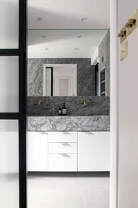 Modern bathroom featuring a marble countertop and vanity with white cabinets.