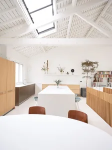 A modern, minimalist kitchen with white marble countertops and a large white marble island.