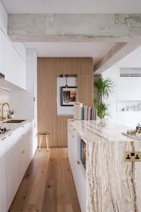 Modern kitchen with marble countertop and wooden walls.
