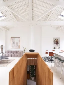 A modern living and dining room with wooden walls and white walls, featuring a wooden partition and a round coffee table in t