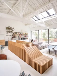 A modern living room featuring wood accents, concrete elements, and large glass windows.