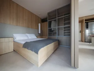 A modern minimalist bedroom with wood furniture and a glass wardrobe.