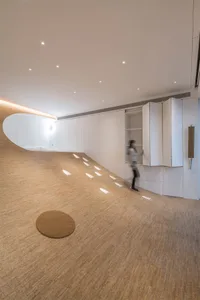 A minimalist living space featuring a wooden floor with unique design elements, including a circular area rug and a winding p