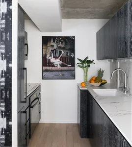 A modern minimalist kitchen with black-wood cabinetry and white-marble countertops, featuring a sink with fruits and a framed