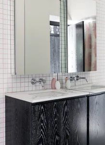 Modern bathroom with white and black marble tiles, black cabinets, and chrome faucets.