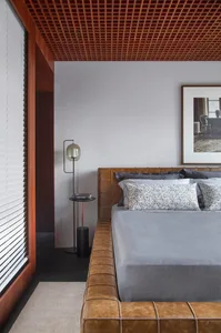 A minimalist grey bed room with a leather frame bed, white blinds, and a black floor, featuring grey bedding and black metal