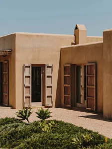 A modern building with earth-toned walls and large wooden doors and windows.