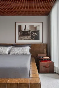 Minimalist bedroom with a large bed featuring a leather headboard, floral-patterned bedding, and a wooden nightstand with boo