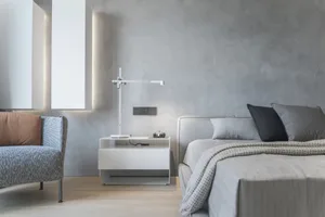 A minimalist bedroom designed with concrete walls and a modern light fixture, featuring a comfortable bed with gray bedding a