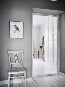 A minimalist interior with gray walls, a white wooden door, and a black and white bird painting.