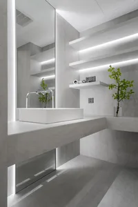 Minimalist modern bathroom with white concrete walls and floor, sleek white square sink, and floating white shelves with buil