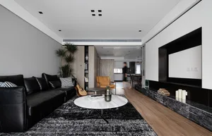 A modern living room featuring a black leather couch and a white marble coffee table