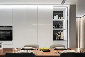 A modern kitchen featuring white glass cabinets, sleek countertops, and a minimalist design.