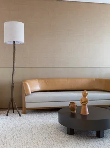 A modern living room with a beige sofa, black coffee table, and decorative statues.