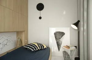 Modern minimalist bedroom featuring a single bed adorned with a black and yellow polka dot pillow against a black and white i