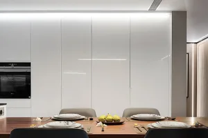 A modern kitchen with white glass tiles on the walls and wooden floor.