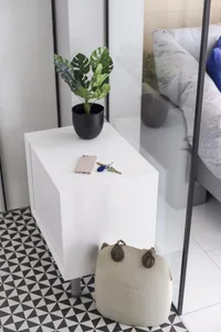 A minimalist bedside table with a potted plant, keys, and a smartphone on it.