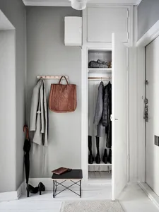 A minimalist entryway featuring concrete flooring, a wooden bench, metal accents, and a closet with wood doors.