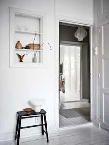 A minimalist interior design featuring a white space with wooden furniture and decorative objects on shelves.