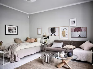 A minimalist living room with light-colored furniture, cushions, and throw blankets.