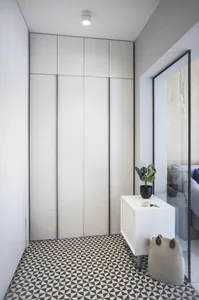 Modern entryway with white cabinets, black trim, and black and white patterned flooring.
