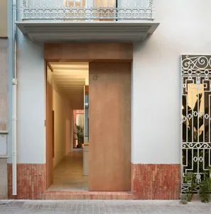A modern residential entryway featuring a wooden door and brick base, viewed from the street.