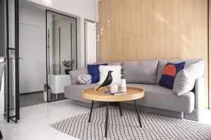 Modern living room featuring a large couch adorned with patterned cushions, surrounded by a wooden coffee table and patterned
