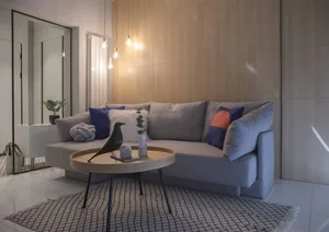 Modern living room featuring a grey sofa with colorful pillows and a round wooden coffee table with a black bird figure.