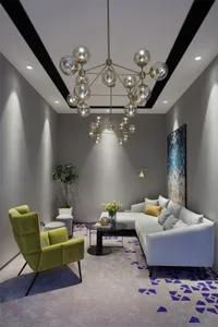 A modern living room featuring velvet furniture, concrete floor, and patterned rug