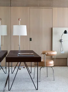 A modern minimalist home office featuring wooden furniture and a white lamp.