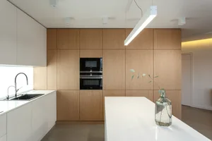 Modern minimalist kitchen with white cabinets and wooden accents.