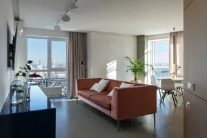 Modern living room featuring a velvet couch and a large window with a city view.