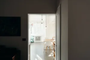 A minimalist interior with white walls, wooden furniture, and a wooden table.