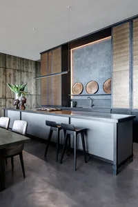 A modern kitchen featuring a kitchen island with a modern design and white and black countertop, surrounded by wooden cabinet