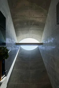 A concrete conduit with a circular opening at the end, showcasing a minimalist architectural design.