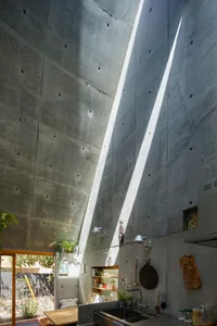 Concrete kitchen interior with modern design elements, featuring a high ceiling and natural light.