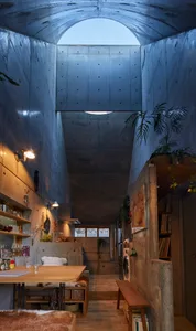 A modern, industrial residential interior with exposed concrete walls and a high, open ceiling, featuring a cozy living area 