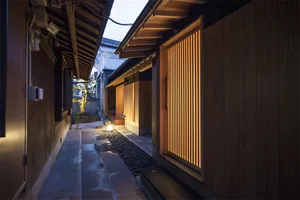 An evening view of minimalist architecture with wooden walls and a gravel pathway.