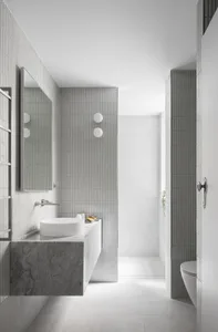 A minimalist bathroom with gray tiles, a standalone sink, and a mirror.
