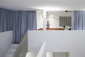 Minimalist living room with concrete walls and floor, featuring a white ceiling and blue curtains.