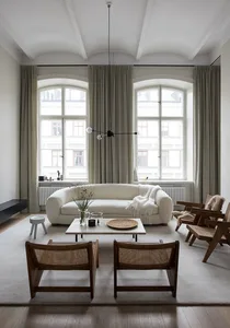 A minimalist living room with neutral-toned furniture and decor, featuring large windows and natural light.