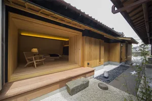 A minimalist residential interior featuring wooden walls and floor, with a comfortable seating area.