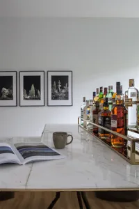 A sleek, modern bar featuring a marble countertop with a variety of alcoholic beverages and an open book.