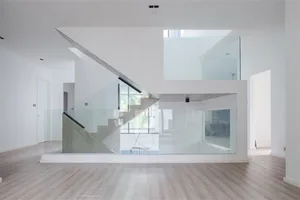 A modern, industrial indoor staircase with glass railings and a minimalist design.
