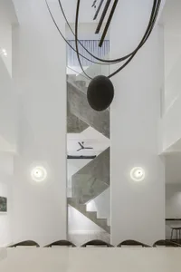 Modern interior design featuring a concrete staircase with a large spherical sculpture hanging above it, set against a minima
