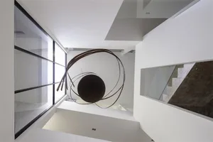 Modern interior design featuring a large metal sculpture with circular patterns hanging from the ceiling.