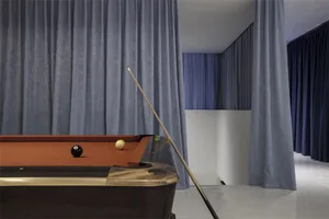 A modern interior featuring a pool table with velvet curtains and a marble floor.