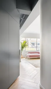 Modern interior design with white walls, a pink sofa, and wood laminate flooring.
